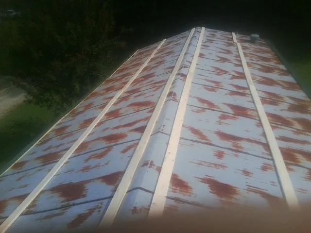 Rusted metal roof panels with new wood purlins before replacement — Storm Damage Roof Repair in Madison Lake by Roofing Brothers