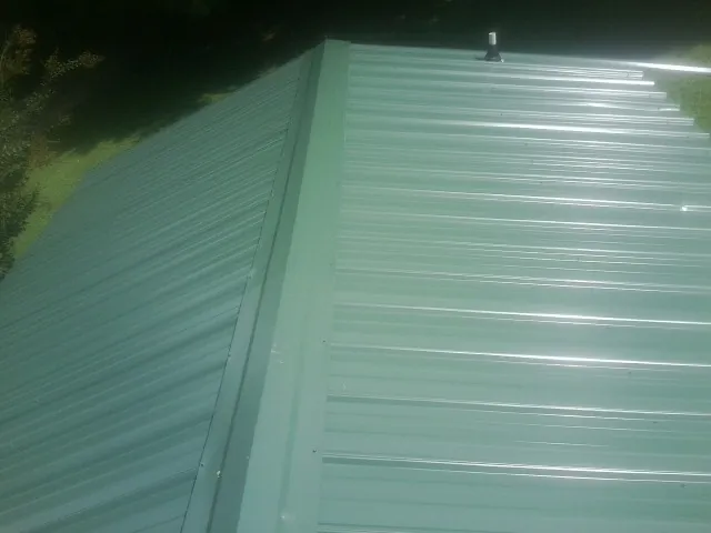 New green metal panels meeting at the ridge of a roof in Madison Lake