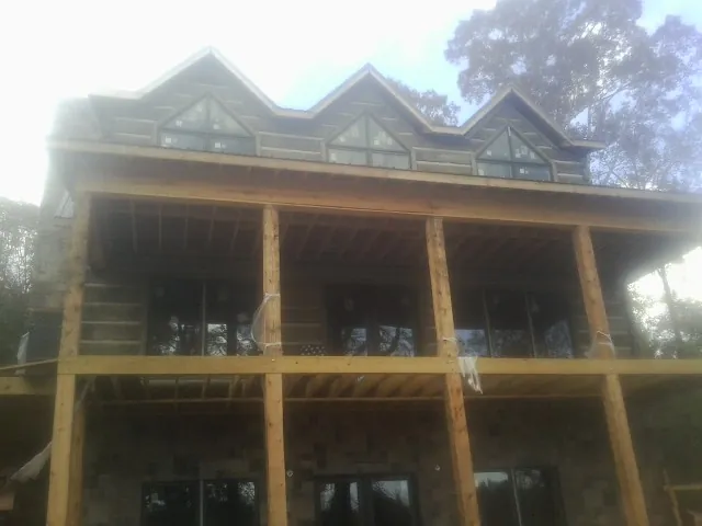 Dormers and porch framing on a large log home under construction — Roof Coating work by our crew in Madison Lake