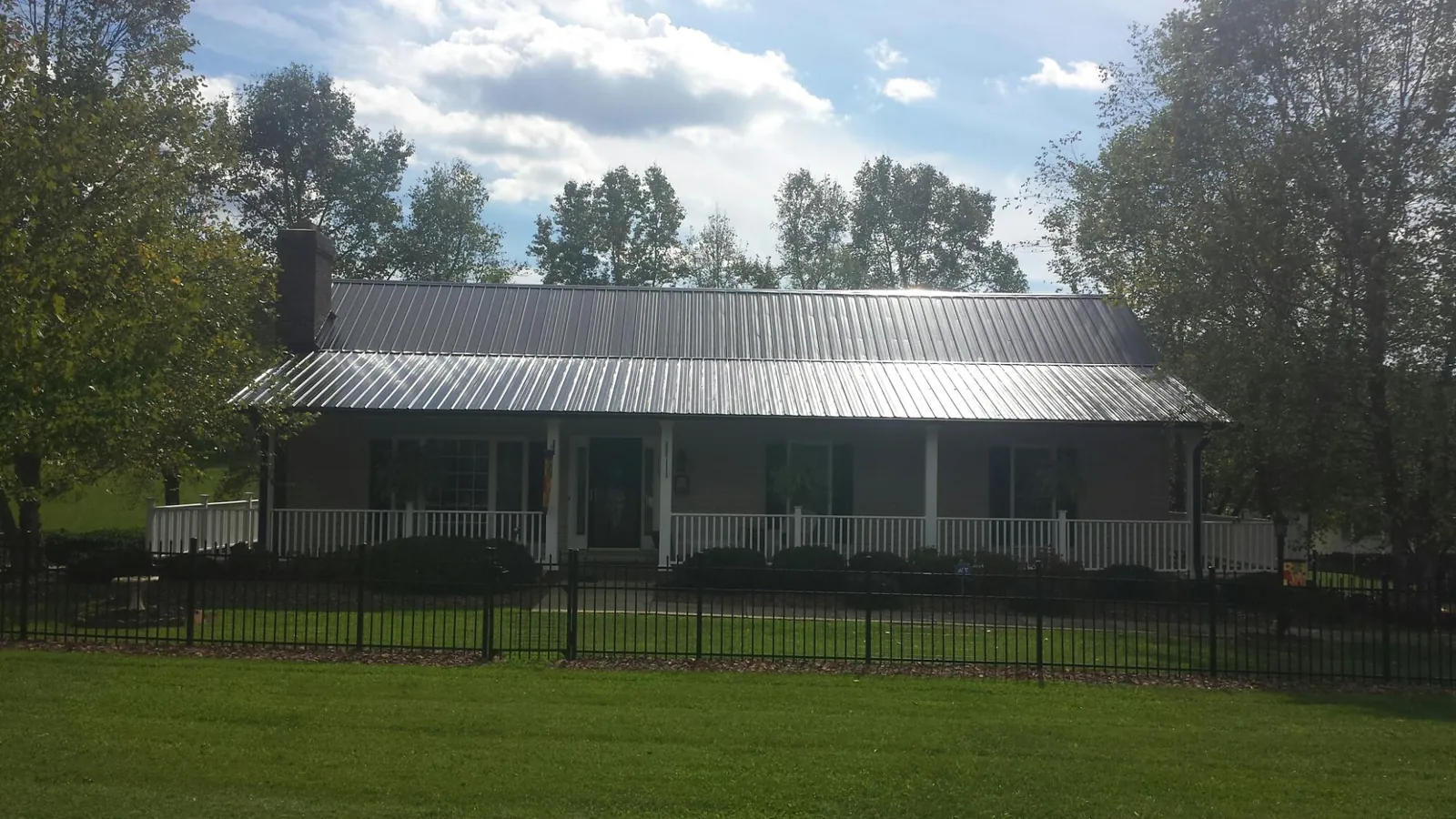 Gray metal roof on a brick ranch with a full width front porch — Gutter Guard Installation work by our crew in Madison Lake
