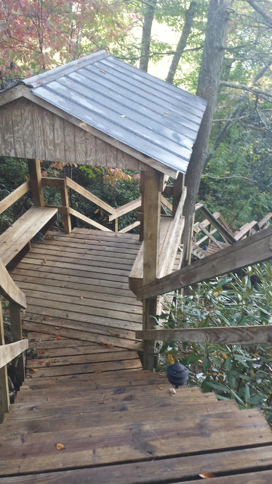 Metal roofed shelter over wooden steps on a wooded walkway — Skylight Repair & Installation work by our crew in Madison Lake