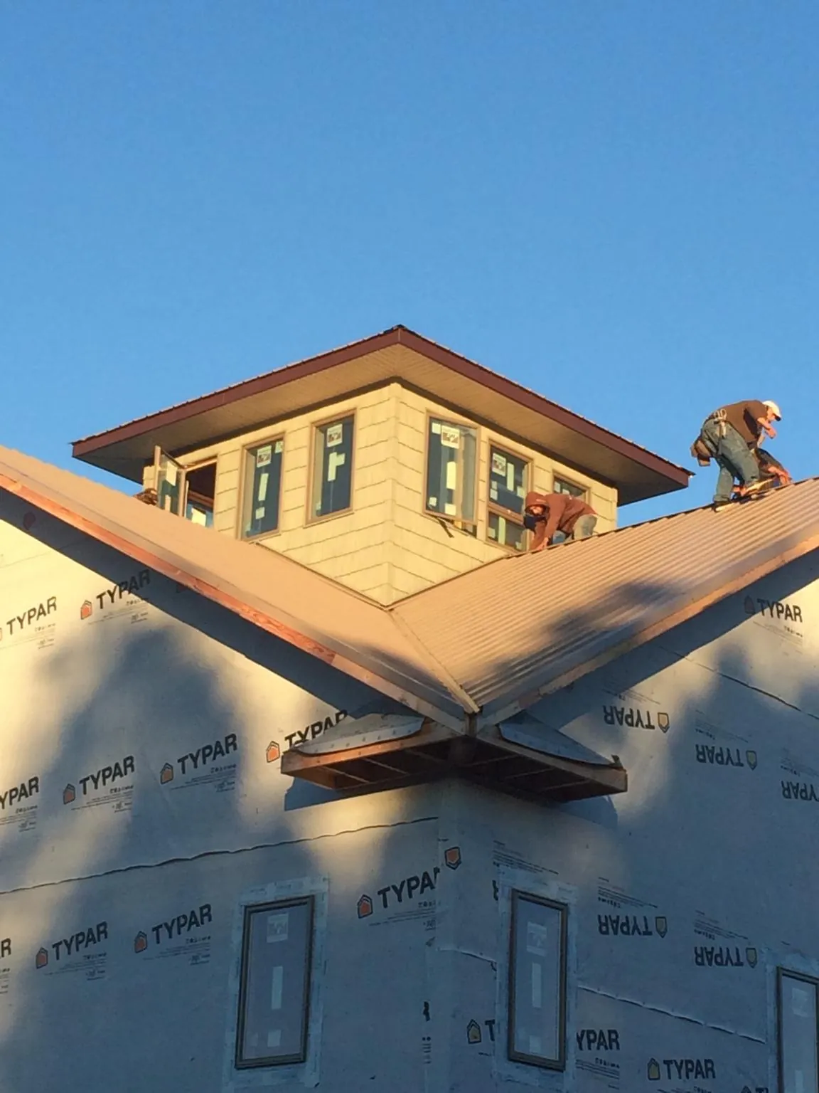 Roofers working around a rooftop cupola on a new metal roof at sunset — Roof Waterproofing in Madison Lake by Roofing Brothers